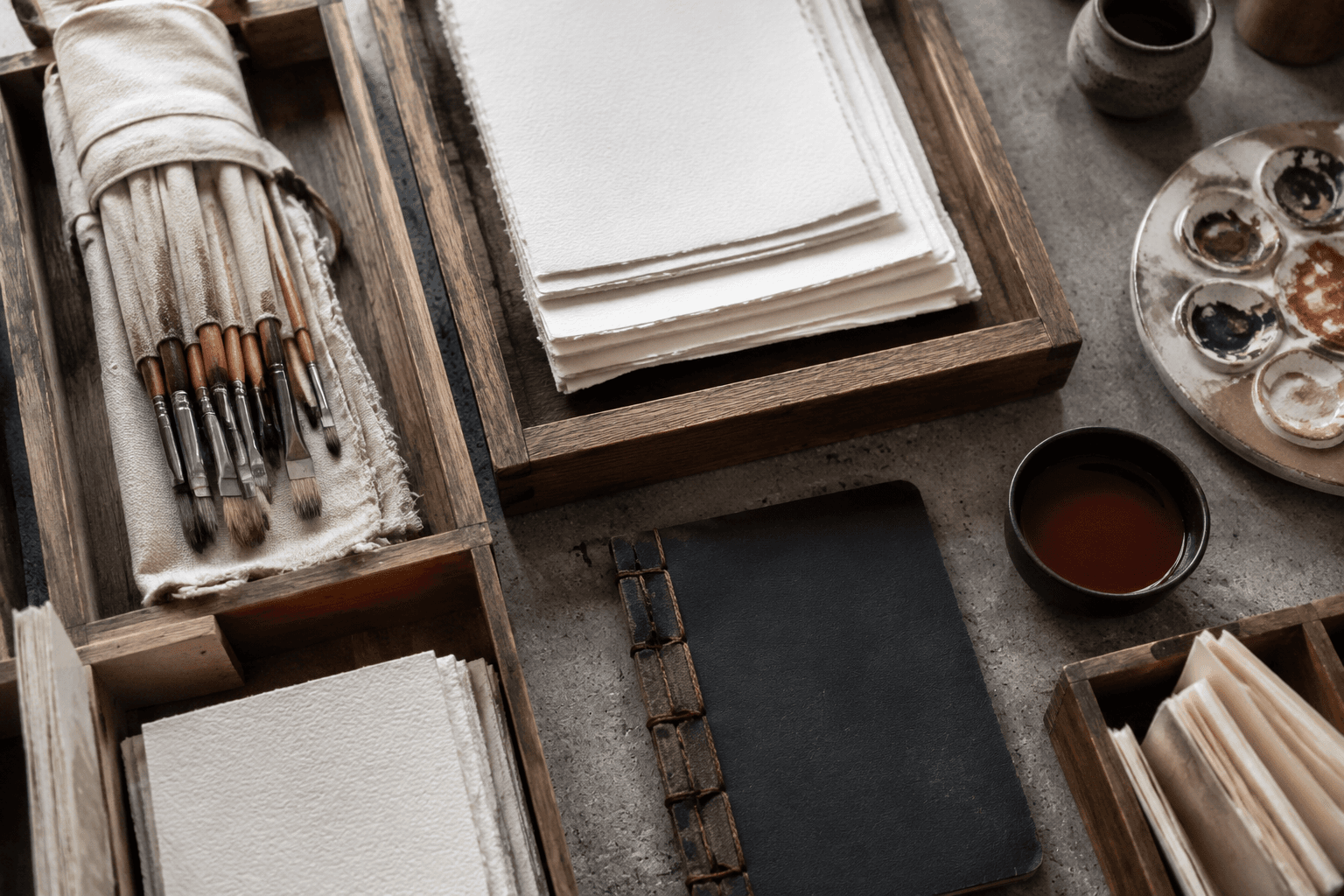 Overhead artist supply counter with paper pads, brushes and palette trays